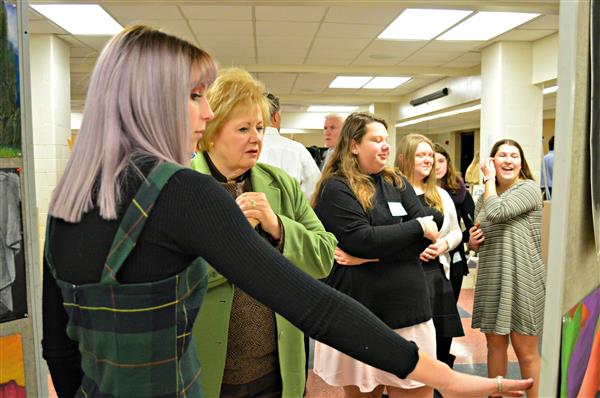 Junior Julia Bush discusses the student art work with community member Karen Barsottini 